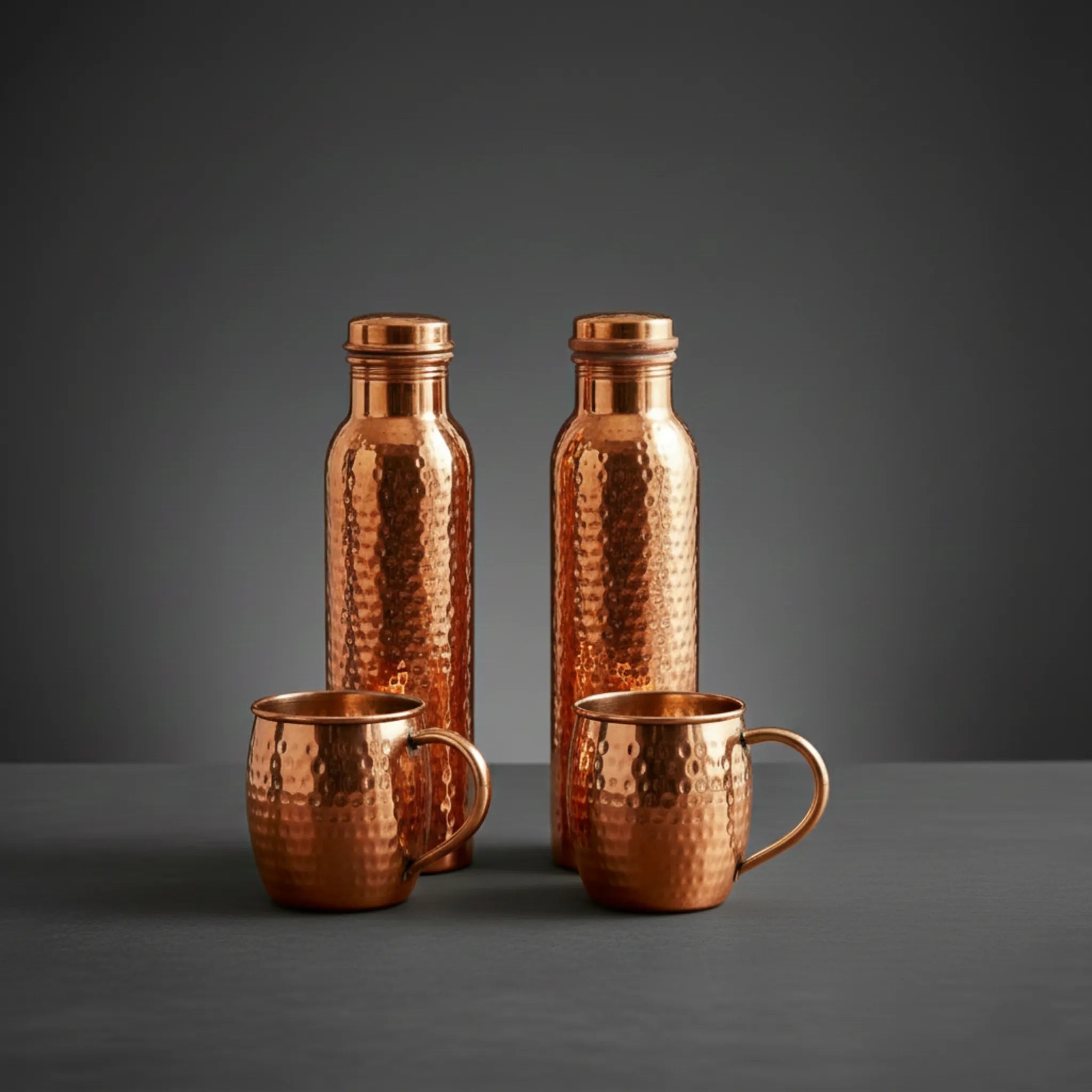 Set of copper bottles and mugs on a dark gray background